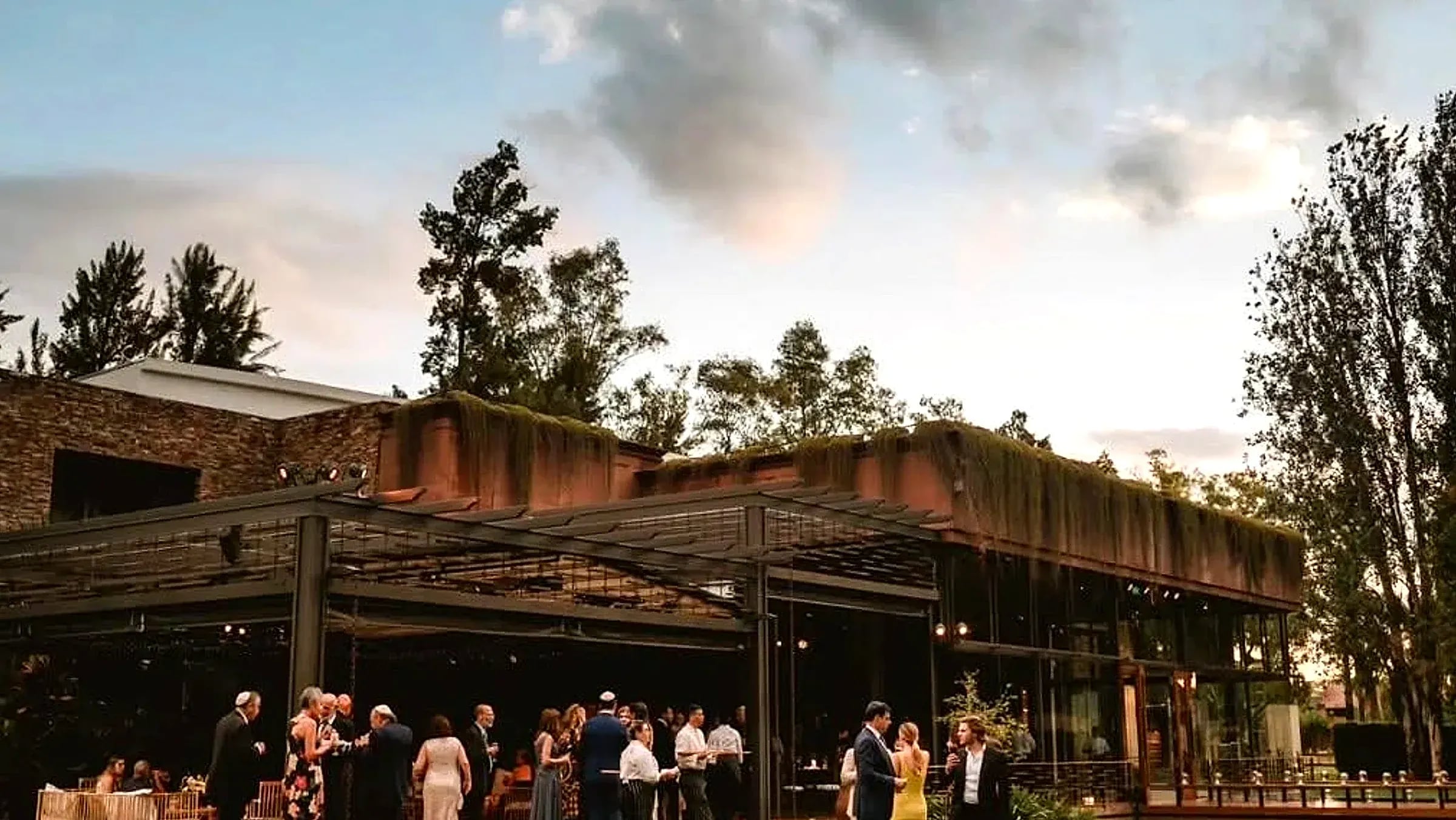 El salón de Rincón entre los árboles, con invitados en el jardín a la hora dorada