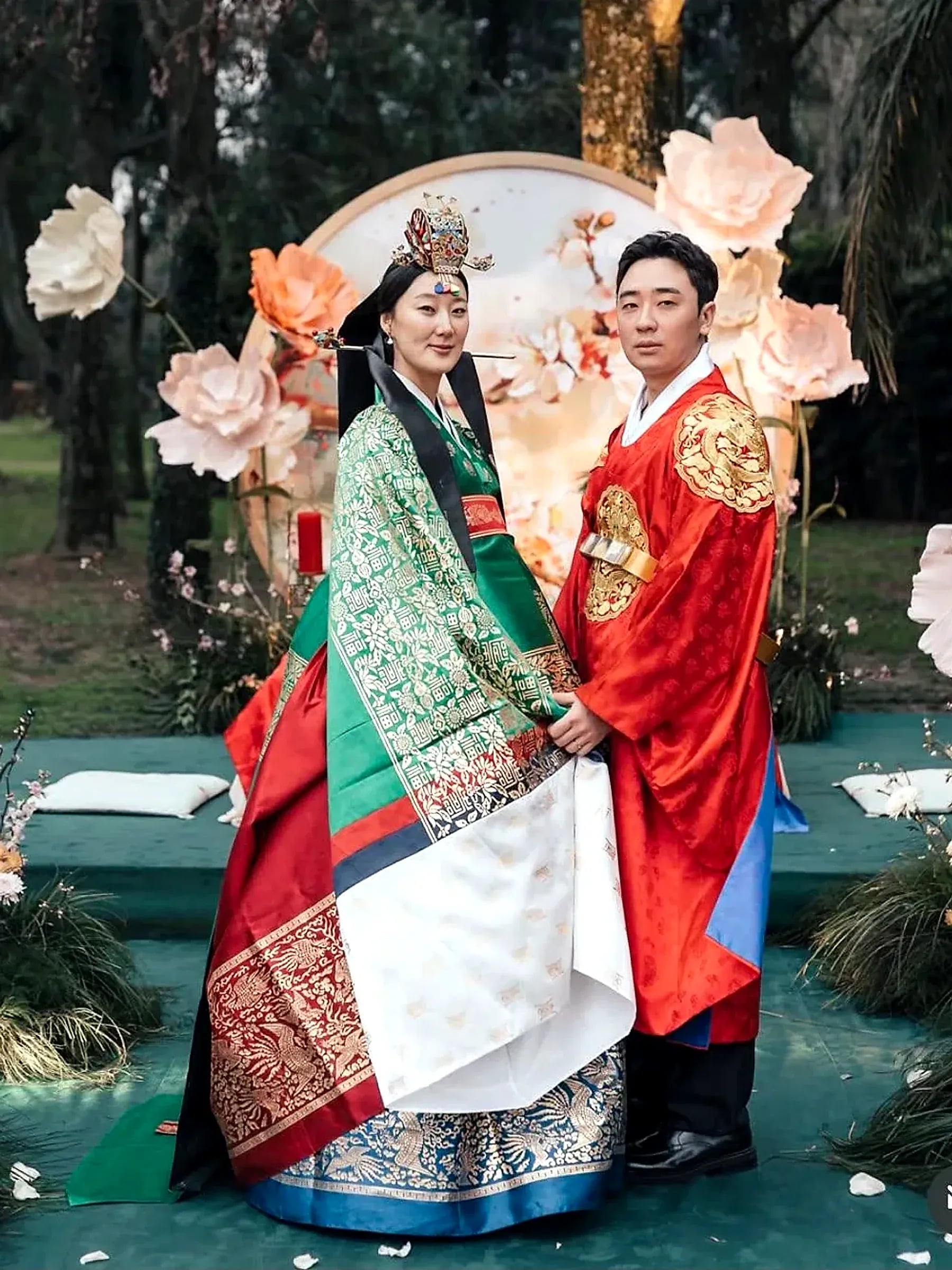 Una pareja posa con trajes tradicionales coreanos frente a un arco floral, durante su ceremonia en Rincón